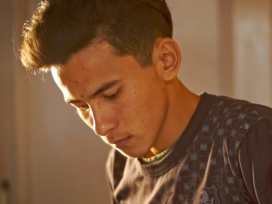 A young man looking down as he builds a guitar.