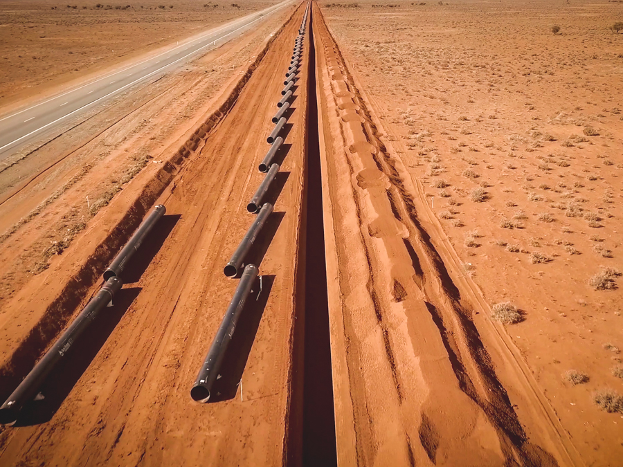 A series of pipes next to a road in the outback.